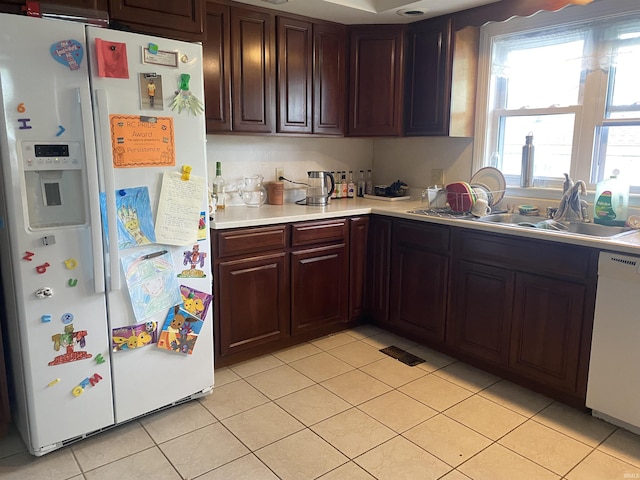 kitchen featuring white appliances, light countertops, light tile patterned floors, and a sink