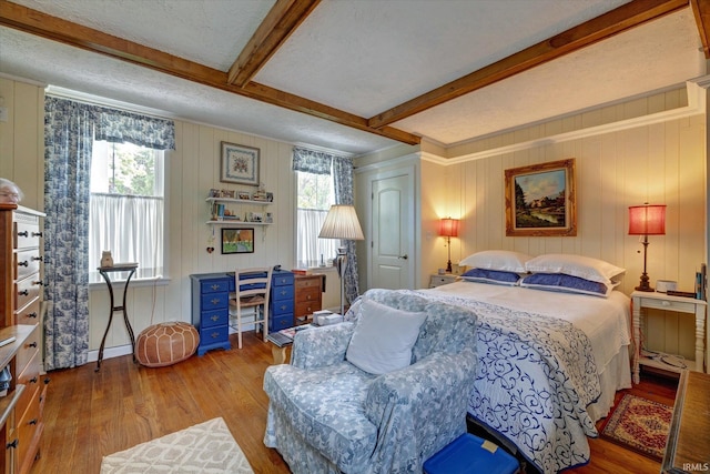 bedroom featuring wood finished floors and beamed ceiling