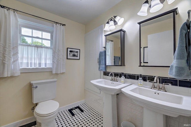 bathroom featuring baseboards, toilet, and a sink