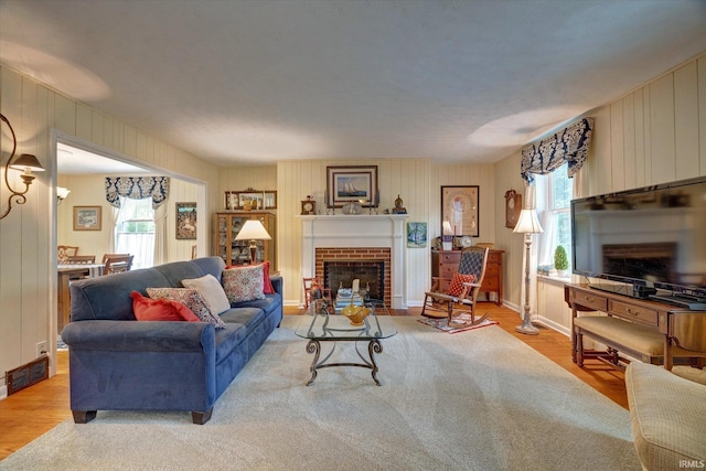 living area with plenty of natural light, a brick fireplace, wood finished floors, and wood walls