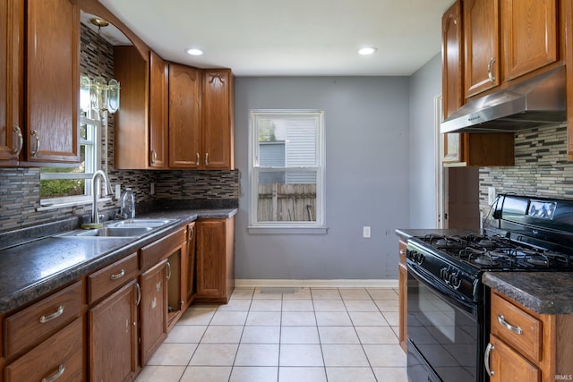 kitchen featuring black range with gas stovetop, under cabinet range hood, a sink, dark countertops, and backsplash