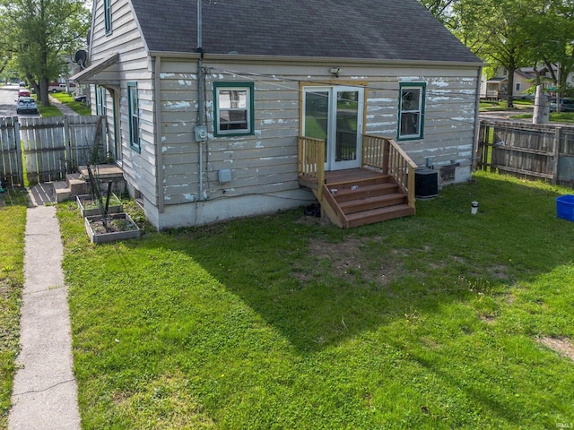 rear view of house featuring a shingled roof, central AC unit, and a garden