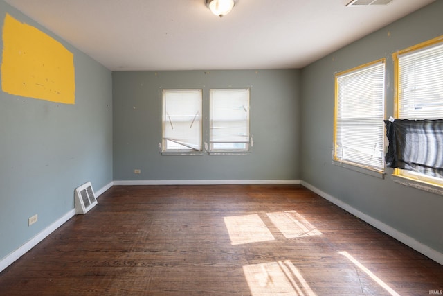 empty room featuring plenty of natural light, wood finished floors, and baseboards