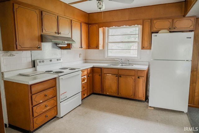 kitchen featuring white appliances, under cabinet range hood, a sink, brown cabinetry, and light countertops
