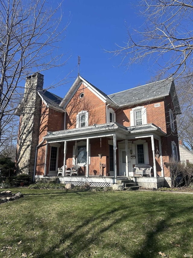 306 Wabash St, Berne, IN 46711 - back of property with brick siding, covered porch, and a lawn