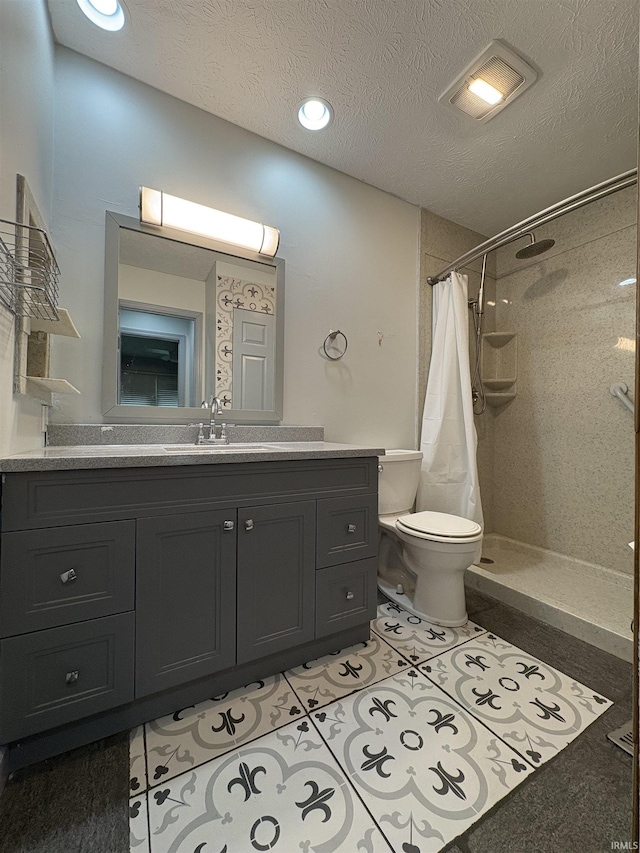 bathroom with a tile shower, toilet, vanity, tile patterned floors, and a textured ceiling