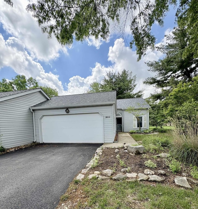 view of front of property featuring an attached garage, asphalt driveway, and a shingled roof