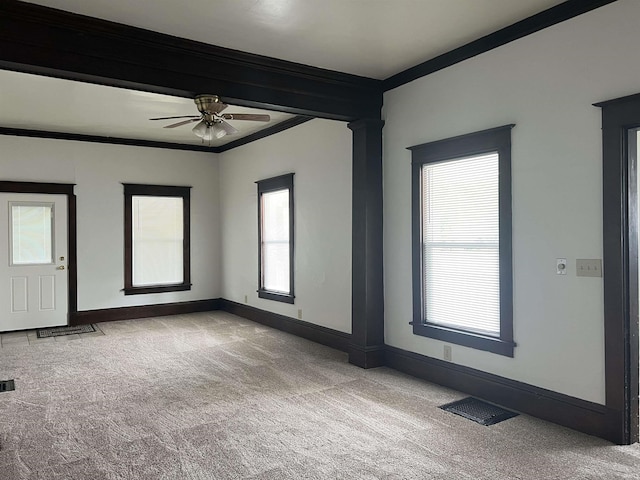 carpeted spare room with crown molding, baseboards, and a ceiling fan