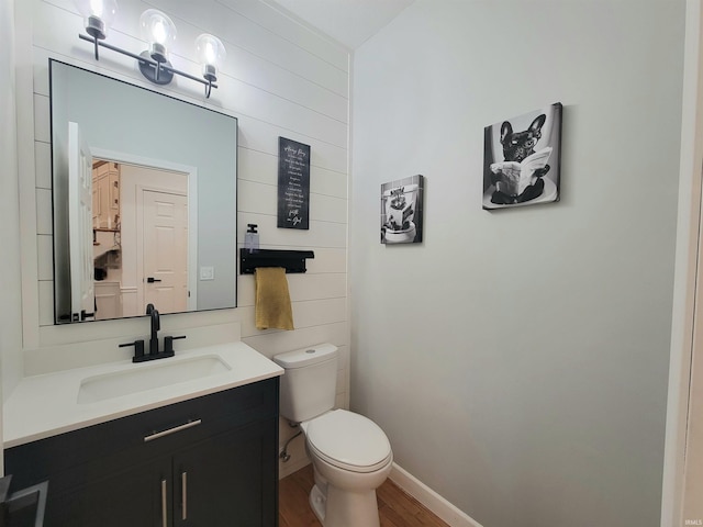 bathroom featuring wood finished floors, toilet, vanity, and baseboards