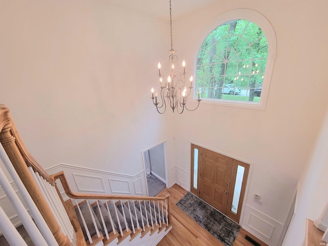 entryway featuring a chandelier, light wood-type flooring, a towering ceiling, and stairway