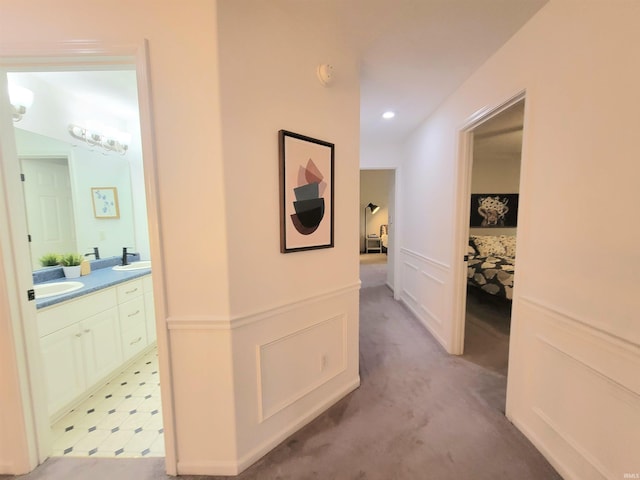 hallway featuring a sink, light carpet, and recessed lighting