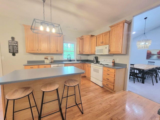 kitchen featuring white appliances, a chandelier, a kitchen bar, and light brown cabinetry