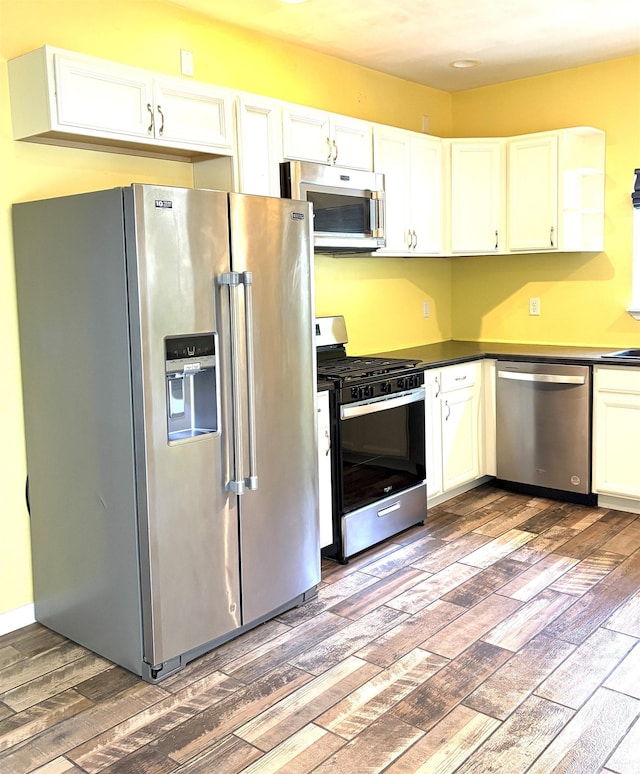 3051 Bluster Ct, West Lafayette, IN 47906 - kitchen with appliances with stainless steel finishes, wood finished floors, dark countertops, and white cabinets