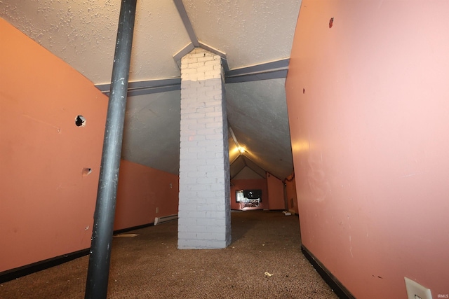 hall featuring vaulted ceiling, carpet flooring, a textured ceiling, and decorative columns