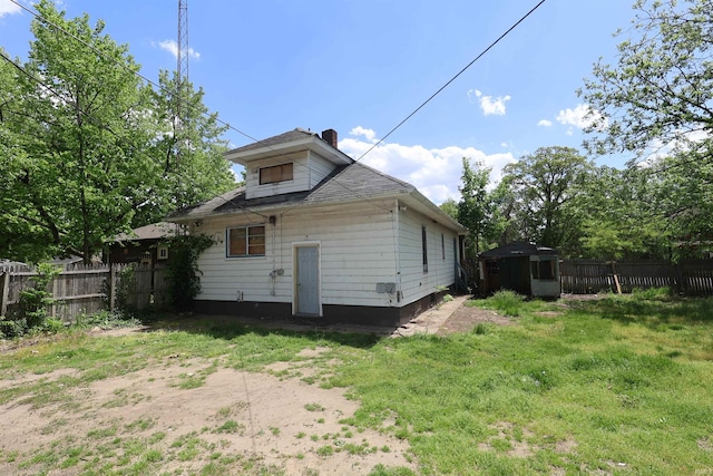 rear view of house with fence, a chimney, a storage shed, and an outdoor structure