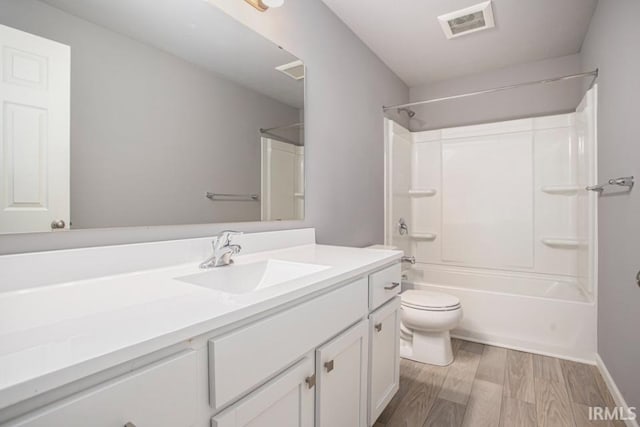 bathroom with toilet, vanity, wood finished floors, shower / bath combination, and baseboards
