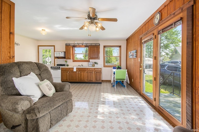 living room with light flooring, a ceiling fan, and baseboards
