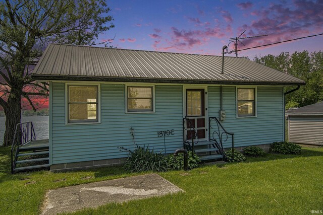 bungalow-style home with a lawn, metal roof, and entry steps