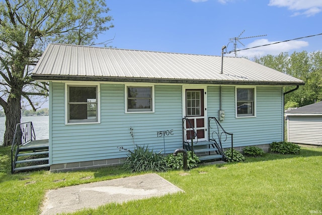 view of front of house featuring a front lawn, entry steps, and metal roof