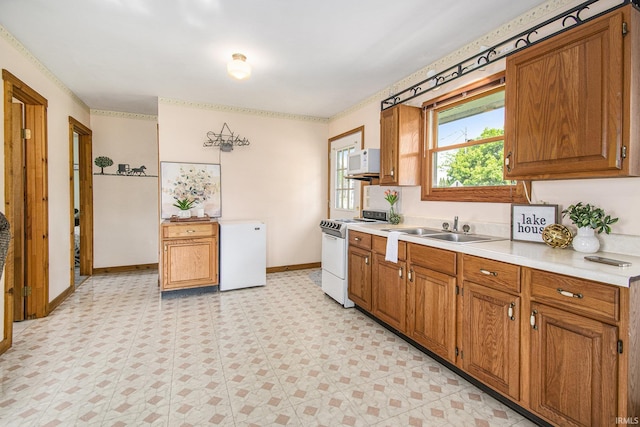 kitchen with white appliances, a sink, light countertops, and brown cabinetry