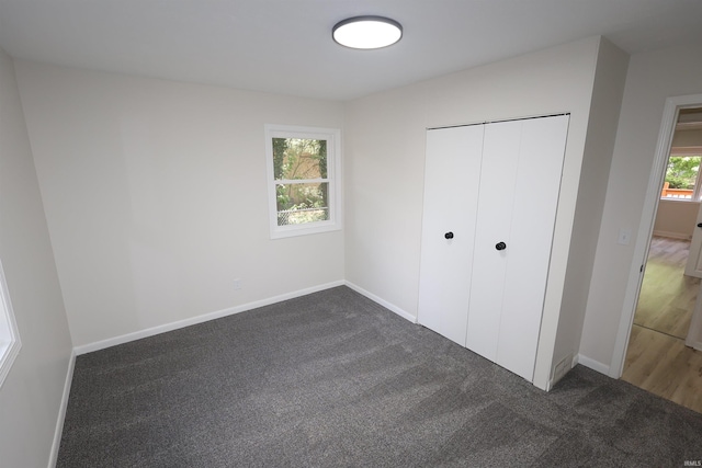 unfurnished bedroom with dark colored carpet, baseboards, and a closet
