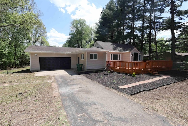ranch-style home featuring asphalt driveway, a garage, and a deck