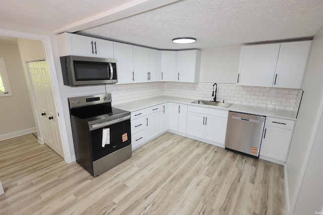 kitchen with stainless steel appliances, a sink, light wood-style floors, light countertops, and a textured ceiling