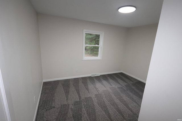 unfurnished room with dark carpet and baseboards