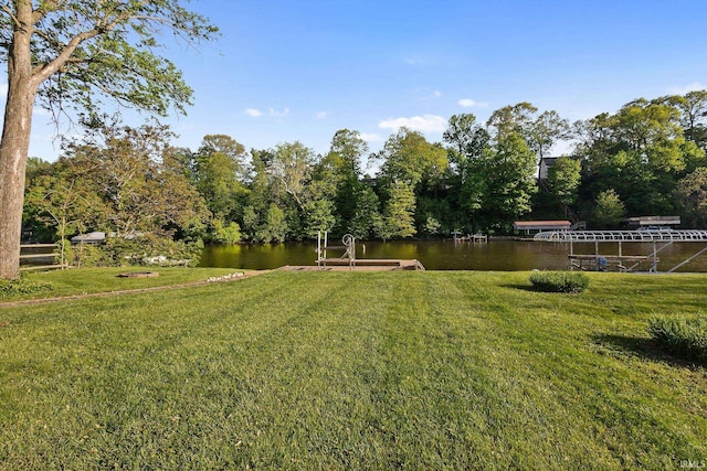 view of green lawn with a water view and a boat dock