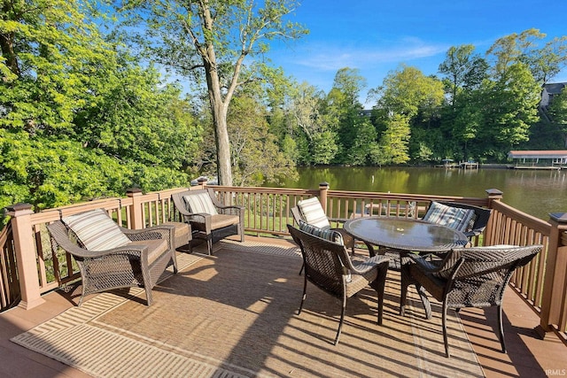 deck featuring a water view, view of wooded area, and outdoor dining space