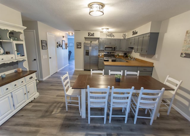 dining space featuring dark wood finished floors, baseboards, and a textured ceiling