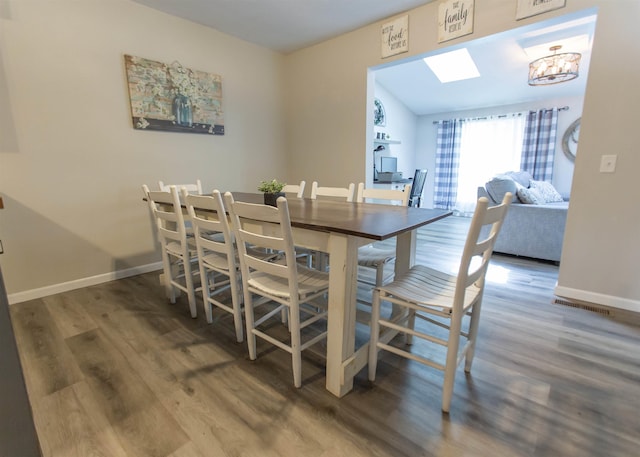dining space featuring wood finished floors, baseboards, and a chandelier