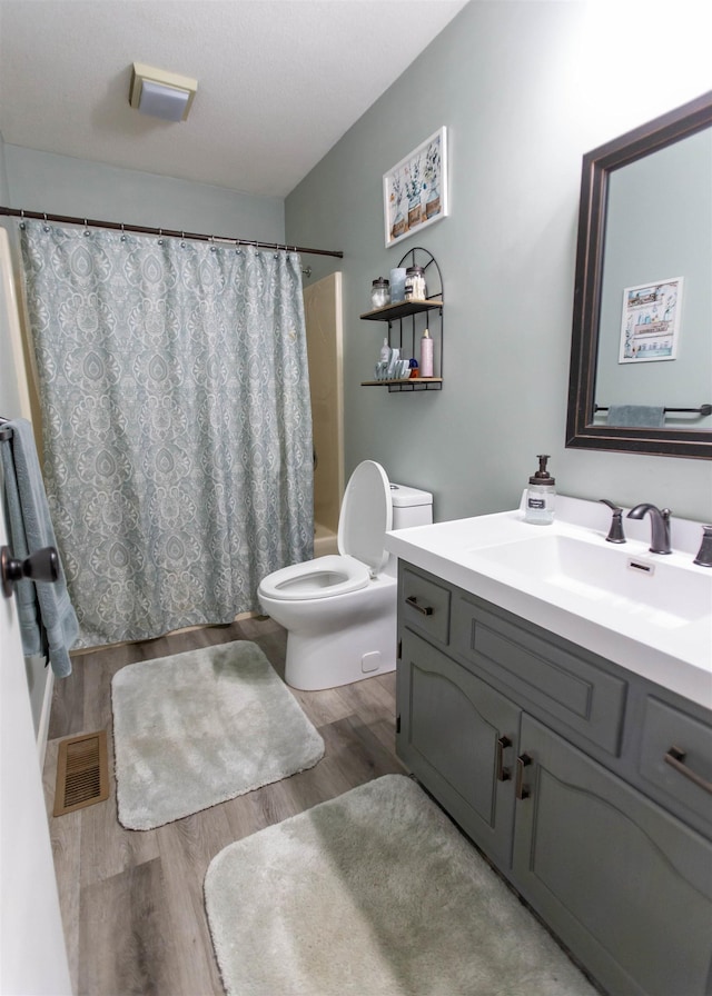 bathroom featuring toilet, wood finished floors, vanity, and shower / bath combination with curtain