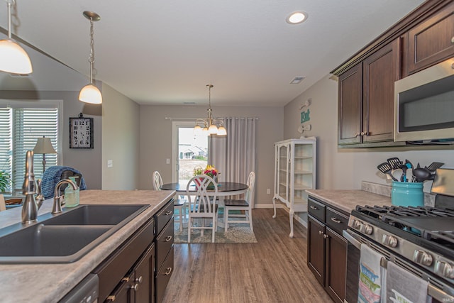 kitchen featuring stainless steel appliances, a sink, wood finished floors, a chandelier, and dark brown cabinetry
