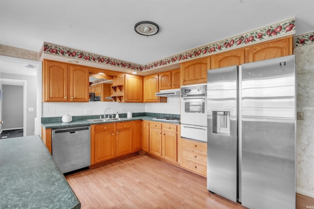 kitchen featuring stainless steel appliances, a sink, a warming drawer, and light wood-style floors