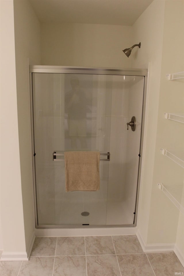 full bath featuring a stall shower and baseboards