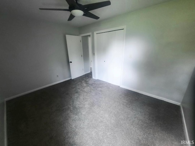 unfurnished bedroom featuring a closet, baseboards, a ceiling fan, and dark colored carpet