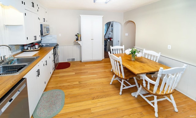 6408 Washington Ave, Evansville, IN 47715 - dining room featuring arched walkways, a wainscoted wall, light wood-type flooring, and a decorative wall