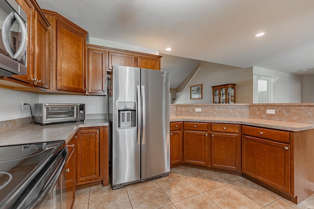 7680 Saint Jordan Cir, Newburgh, IN 47630 - kitchen featuring stainless steel appliances, brown cabinetry, a peninsula, light countertops, and light tile patterned flooring