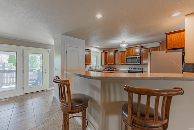 7680 Saint Jordan Cir, Newburgh, IN 47630 - kitchen featuring stainless steel appliances, a textured ceiling, a breakfast bar area, brown cabinetry, and arched walkways