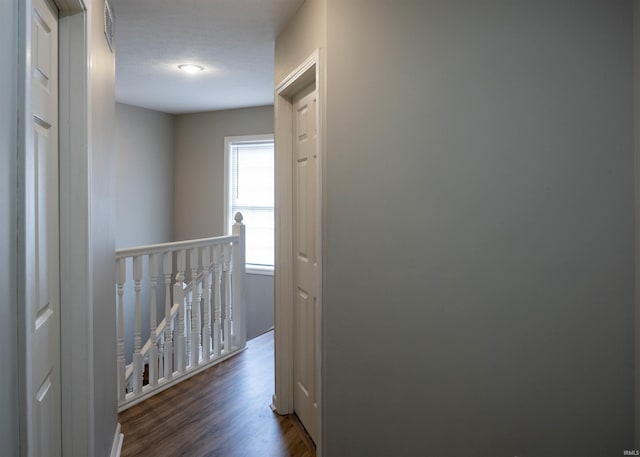 corridor featuring an upstairs landing and dark wood-style flooring