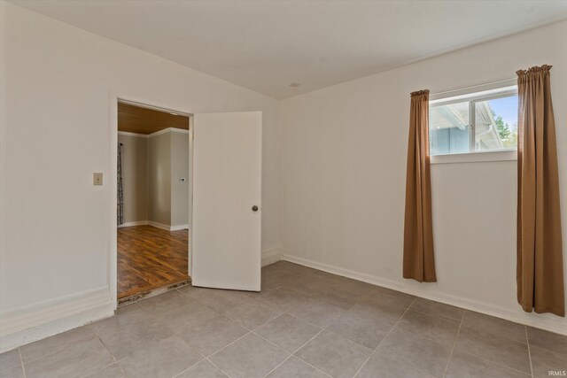 114 S Grand St, Lakeville, IN 46536 - spare room featuring baseboards, tile patterned floors, and vaulted ceiling