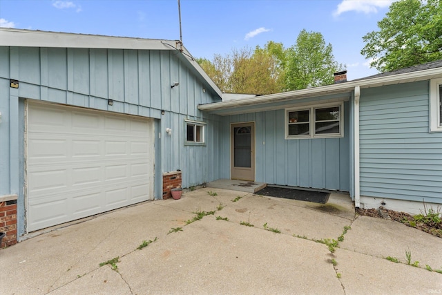 114 S Grand St, Lakeville, IN 46536 - view of front of home featuring board and batten siding, driveway, a chimney, and a garage