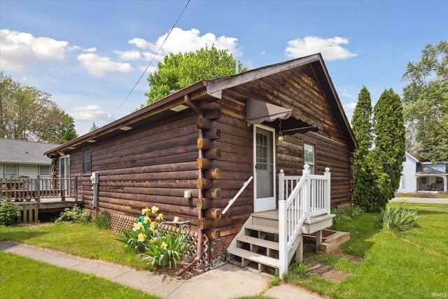 view of side of property with log exterior, a deck, and a yard