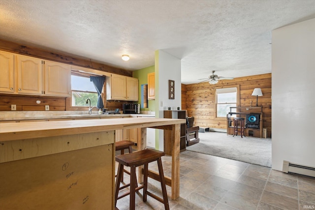 kitchen with butcher block counters, wooden walls, light carpet, light brown cabinetry, and a kitchen breakfast bar