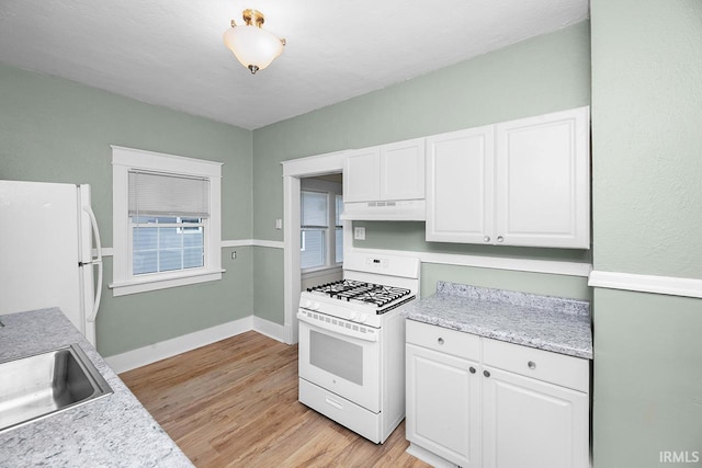kitchen with white appliances, under cabinet range hood, light countertops, white cabinetry, and a sink