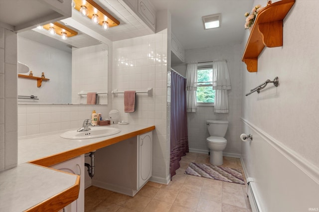 bathroom with a sink, toilet, tile patterned floors, tile walls, and a baseboard radiator