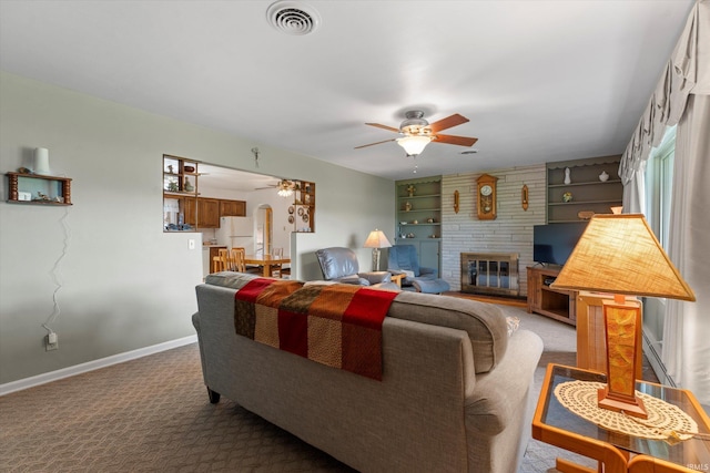 living area with a ceiling fan, baseboards, built in shelves, and carpet floors
