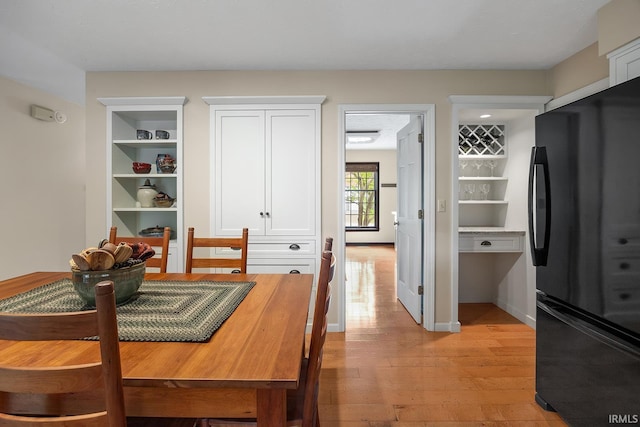 dining area with light wood-style floors, built in features, and baseboards