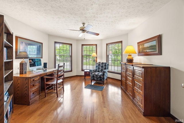 office area with healthy amount of natural light, light wood finished floors, a ceiling fan, baseboards, and a textured ceiling